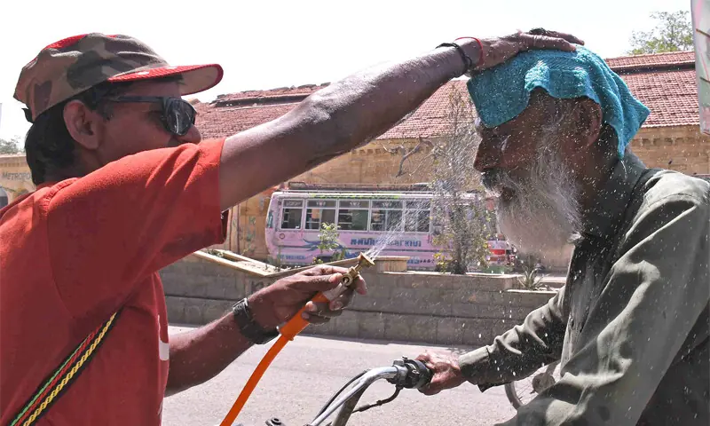 Voluntário borrifa água em transeunte durante onda de calor em Karachi