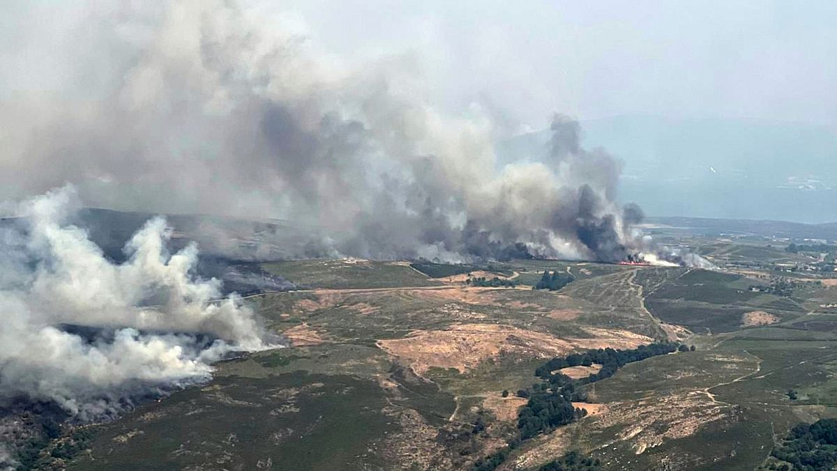 Bombeiro combate incêndio florestal na Espanha, com fumaça densa ao fundo