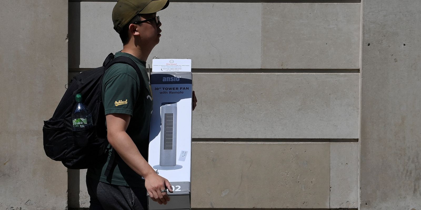 Homem carrega um ventilador durante onda de calor no distrito financeiro de Londres, Reino Unido