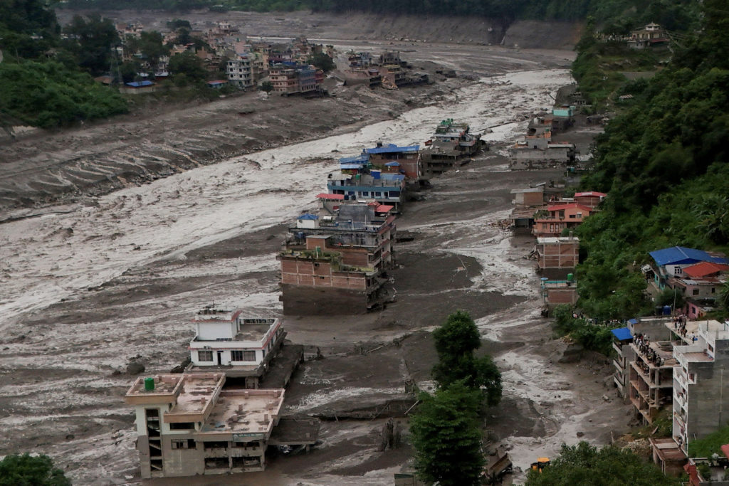 Área devastada pela enxurrada do Bhotekoshi no Nepal, com destroços e lama cobrindo o vale