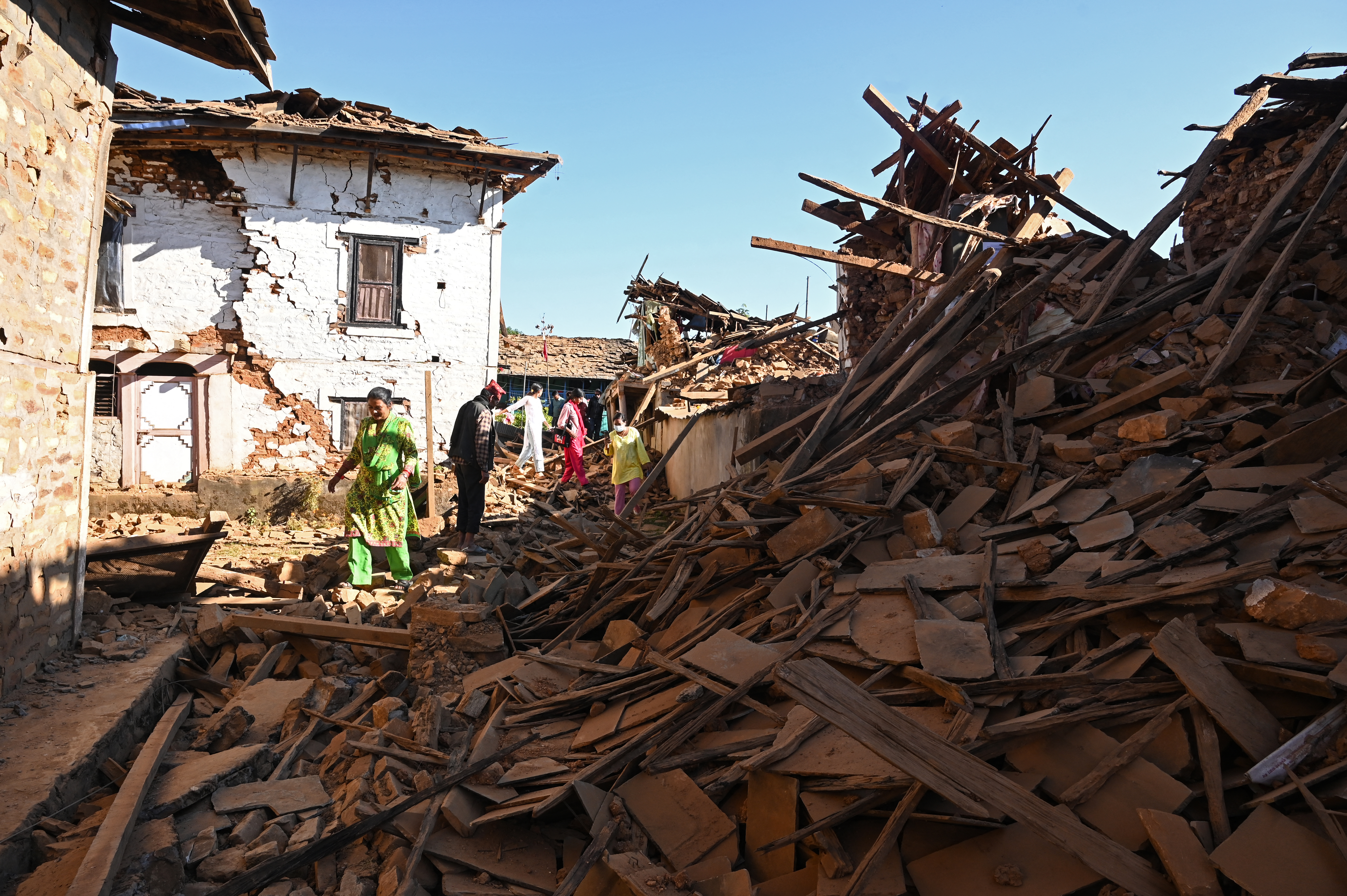 Pessoas caminham entre as ruínas de casas destruídas pelo terremoto no distrito de Jajarkot, Nepal