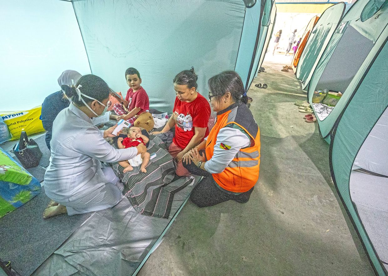 Moradores afetados por enchentes em abrigo de emergência na Malásia