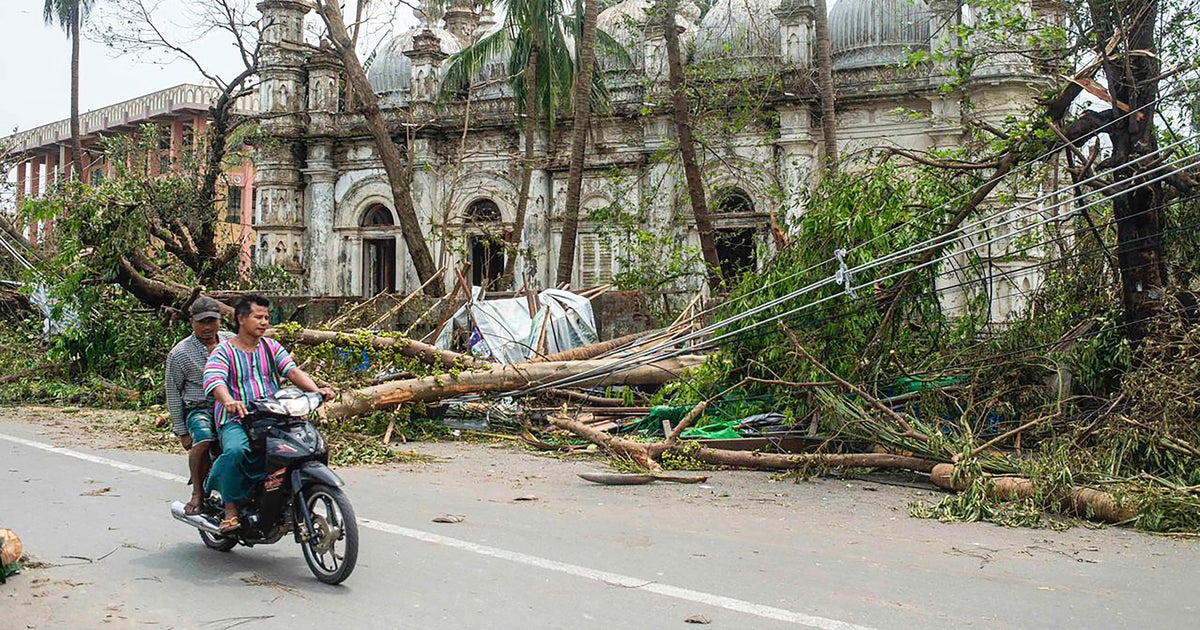Moradores andam de moto entre árvores caídas após a passagem do Ciclone Mocha em Sittwe, estado de Rakhine, Myanmar