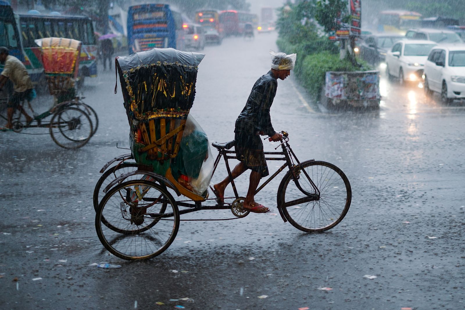 Ciclista atravessa rua urbana durante chuva forte